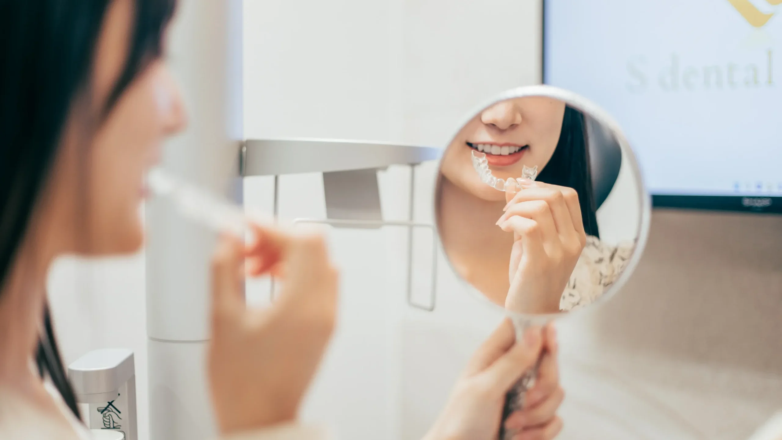 マウスピースの具合を手鏡で見て確かめる女性