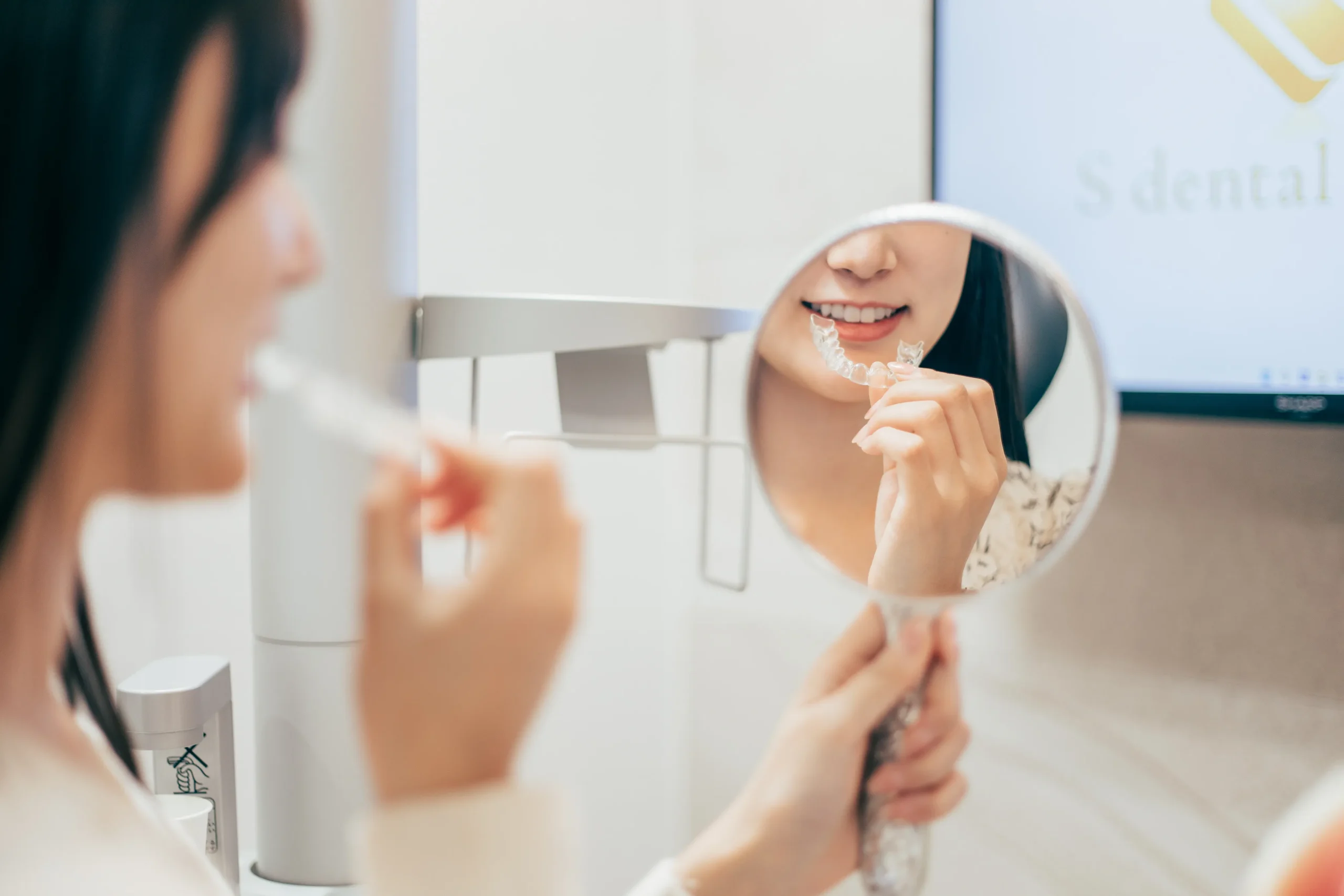 マウスピースの具合を手鏡で見て確かめる女性